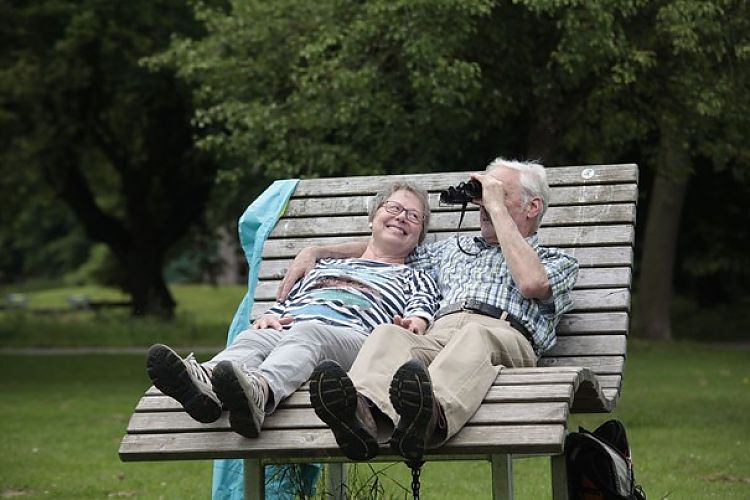 Ein älteres Paar liegt auf einem Liegestuhl und beobachtet mit Fernglas die Natur