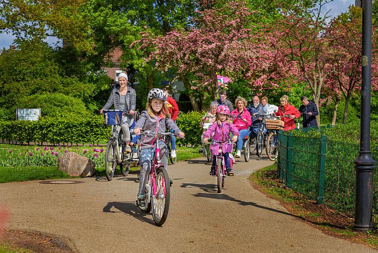 Fahrradfahrergruppe mit Kindern, älteren Menschen, Fahrradanhänger und Tandem