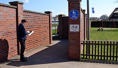 Ein Mann auf einem Fuß- und Radweg notiert etwas auf einem Tablet