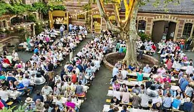 Weinfest in einem Innenhof mit vielen Menschen, die auf Bänke sitzen